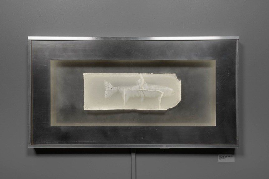 A painting is hanging on a wall in a metal frame.