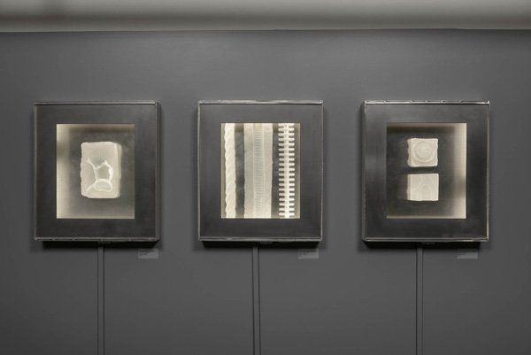 Three black and white paintings are hanging on a wall.