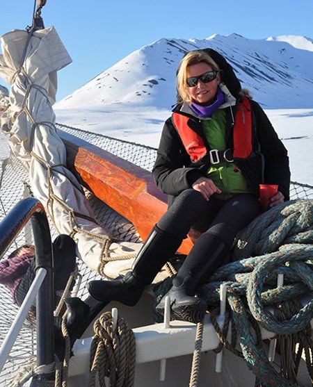 A woman sits on a boat with a mountain in the background