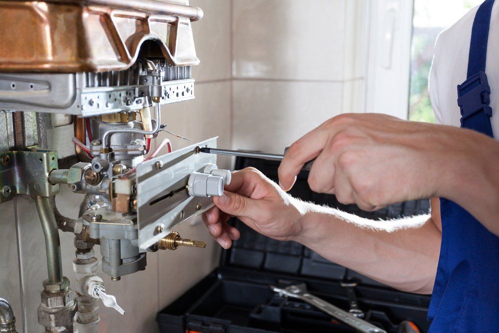 Repairman Fixing A Gas Water Heater — Dempsey Plumbing in Lake Haven