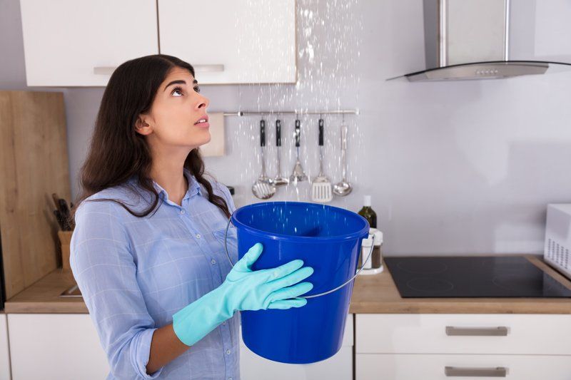 Woman Holding Bucket While Water Droplets Leak — Dempsey Plumbing in Narara