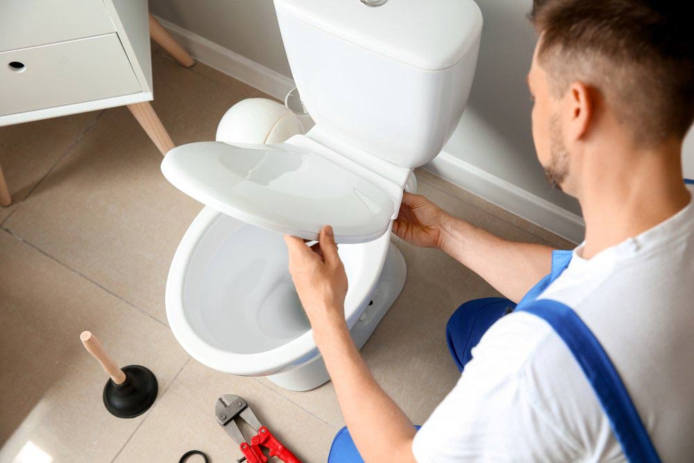 Plumber Installing Toilet In Restroom — Dempsey Plumbing in Woy Woy