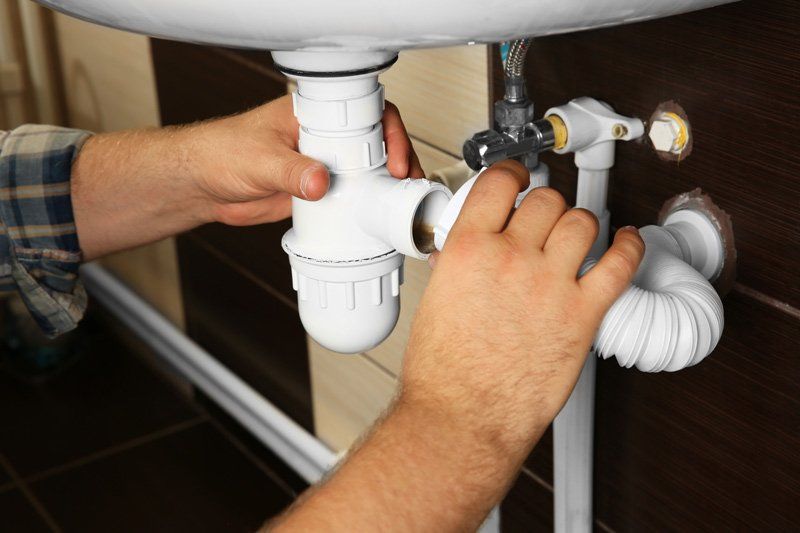 Plumber Connecting Pipes Under The Sink — Dempsey Plumbing in Terrigal
