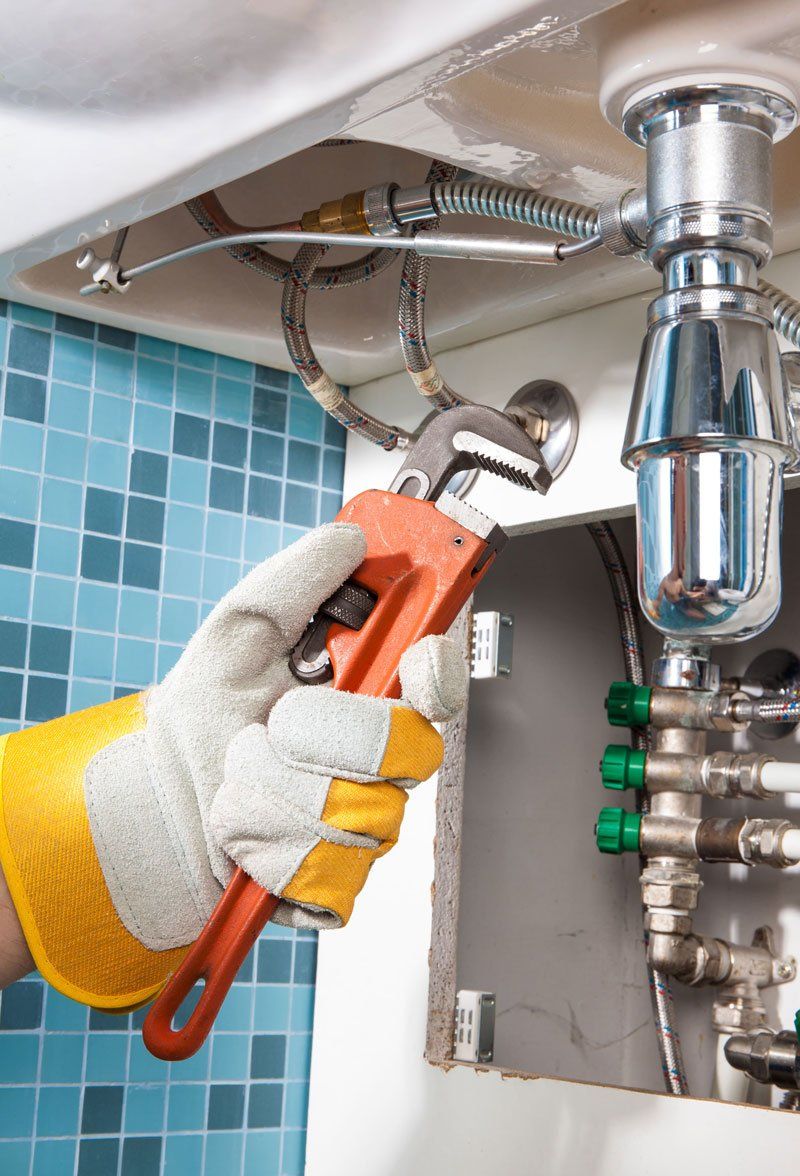 Plumber Holding A Tools Repairing A Pipe Under Sink — Dempsey Plumbing in Terrigal