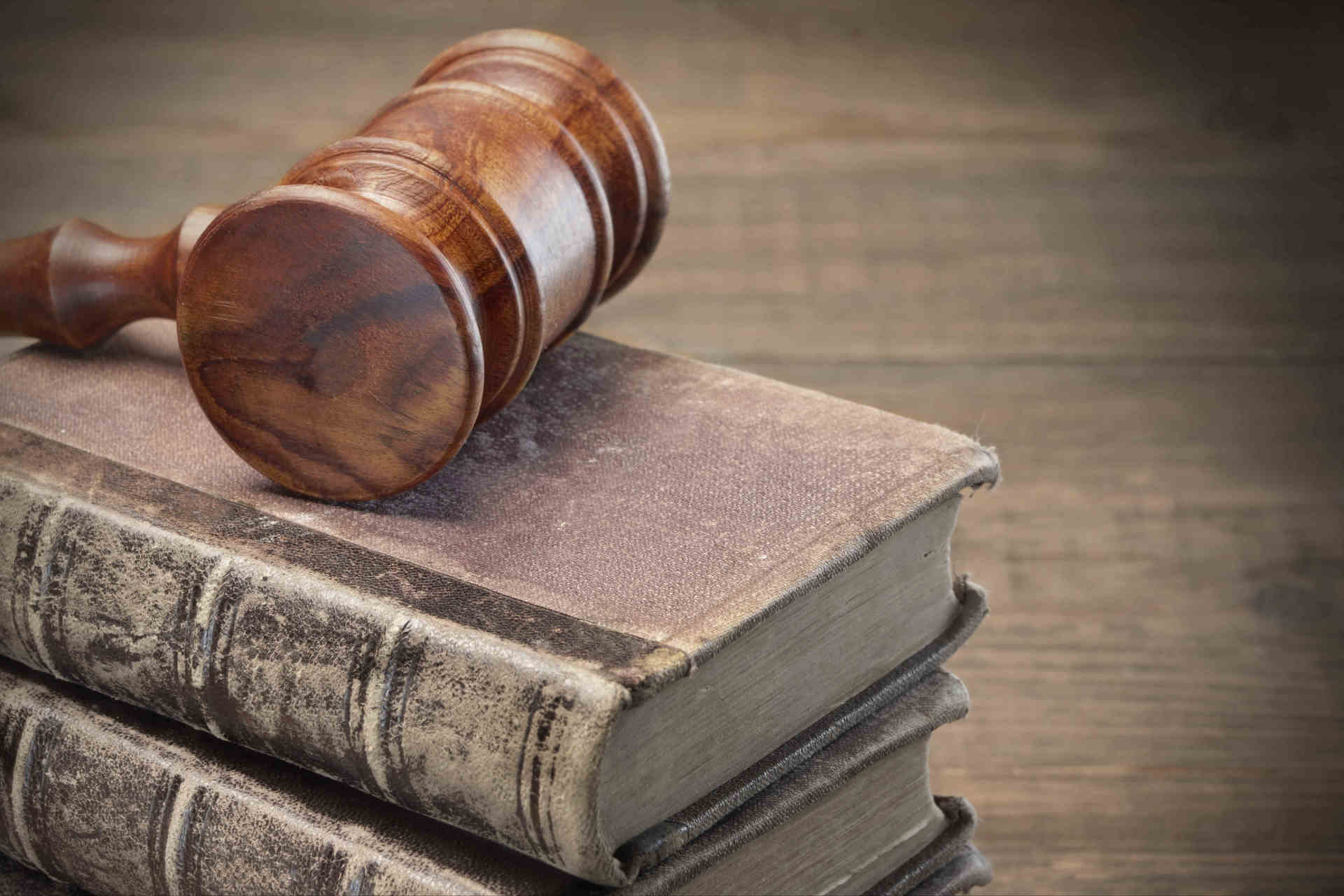 Auf einem Stapel alter Bücher liegt ein hölzerner Richterhammer.