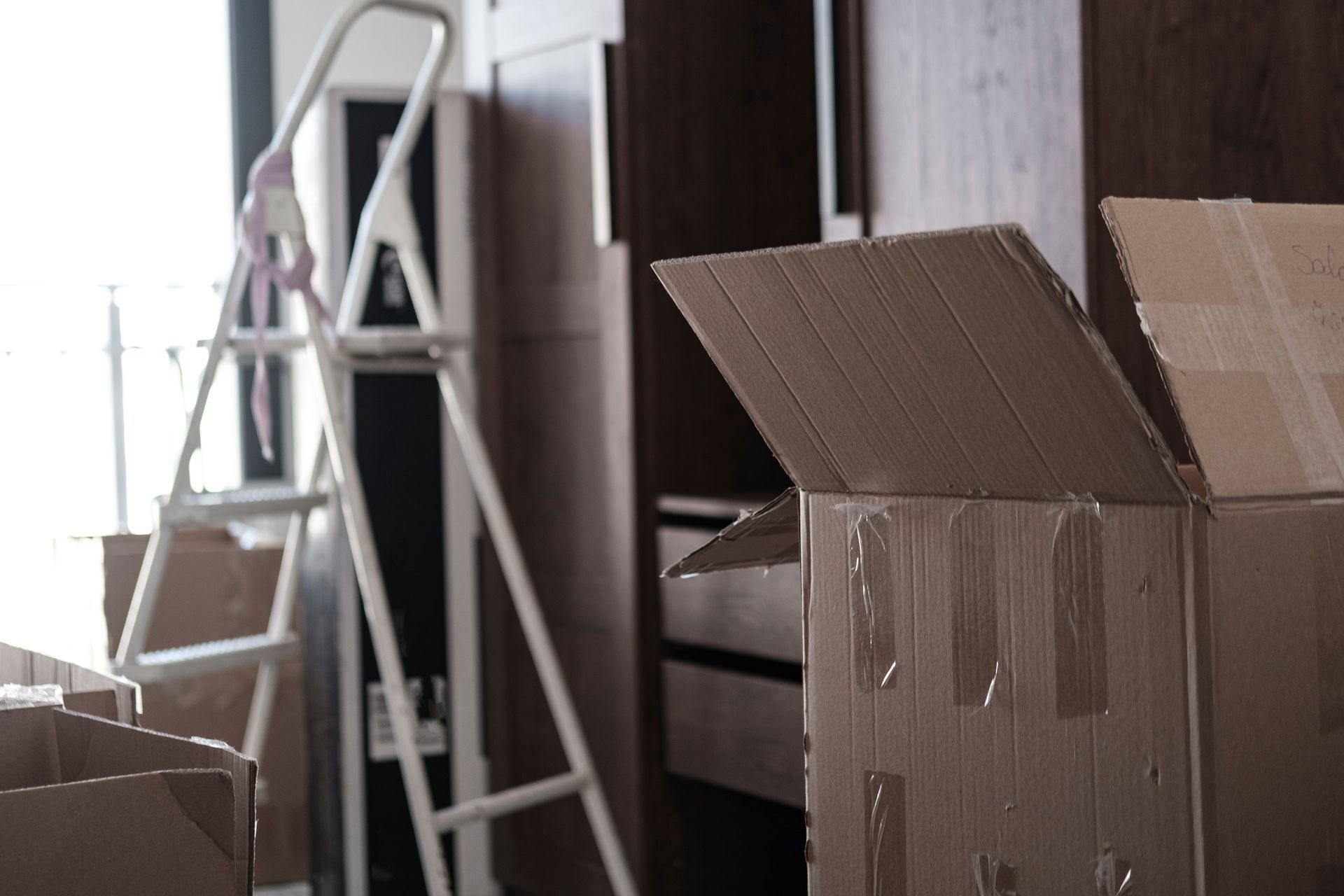 A room filled with cardboard boxes and a ladder.