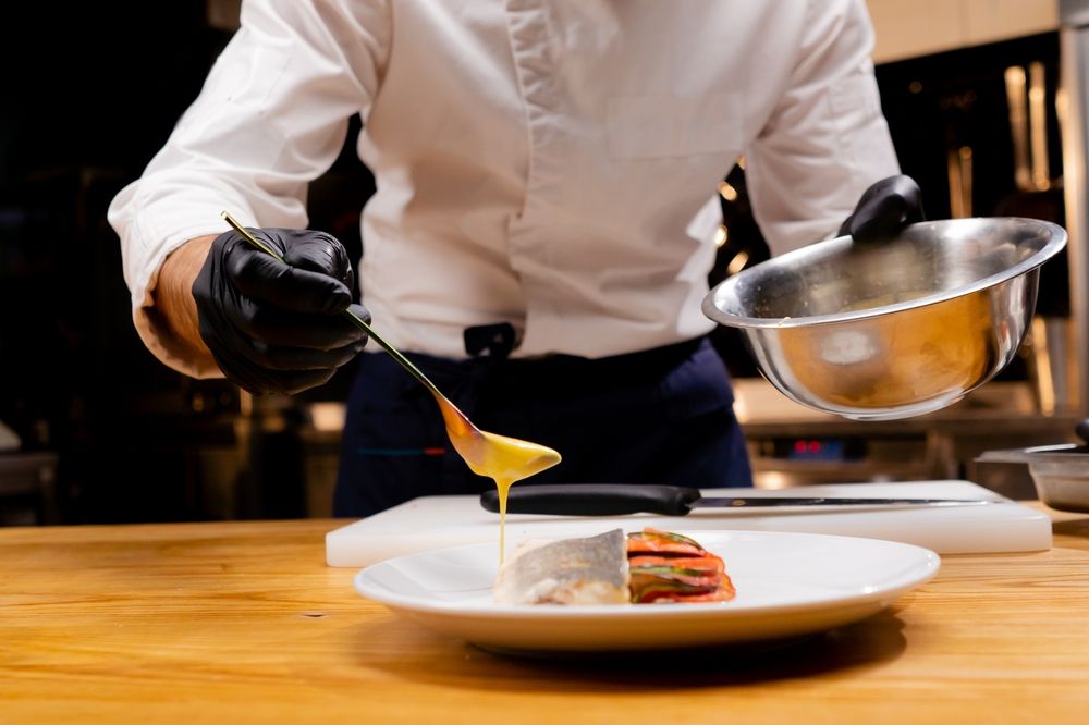 A chef is preparing a plate of food in a kitchen.