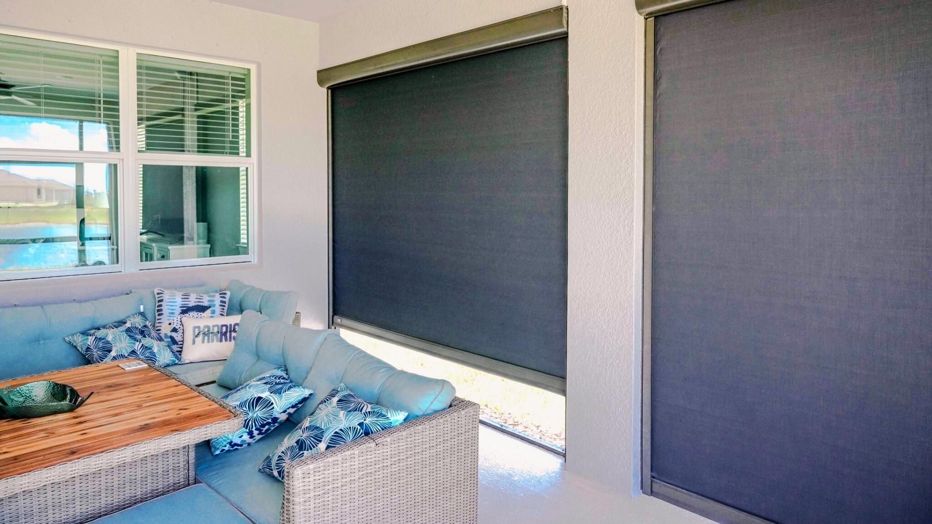 Outdoor patio with seating, table, and closed dark gray roller shades.