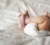 Baby's feet and diaper on a white, textured blanket.