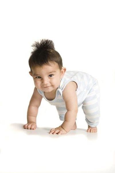 Baby crawling on a white surface, wearing striped blue and white outfit, with a curious expression.