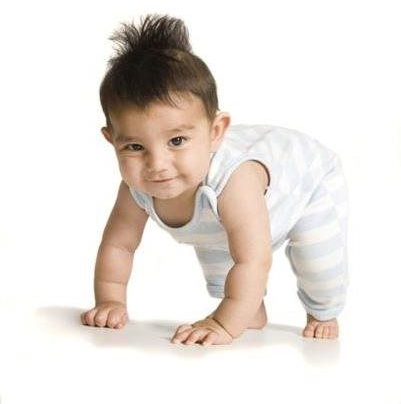A child in a colorful striped shirt lies on a light floor, smiling, surrounded by scattered plastic building blocks.
