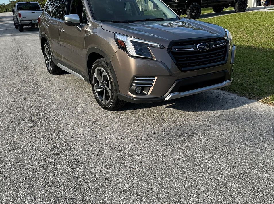 Person wearing black gloves applying ceramic coating to a car's hood.