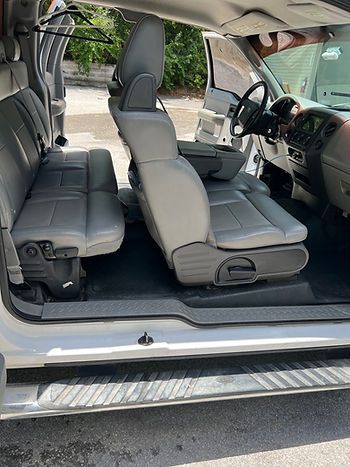 Interior view of a gray truck with two rows of seats. Open doors reveal the vehicle's inside.
