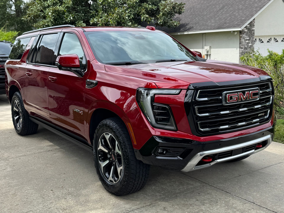 Red GMC Yukon SUV parked on a concrete driveway.