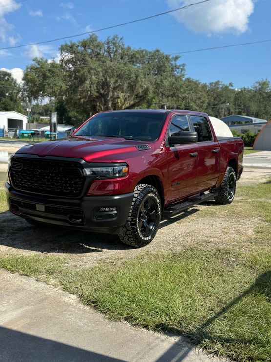 Red Ram truck with black grille and wheels parked on grass.