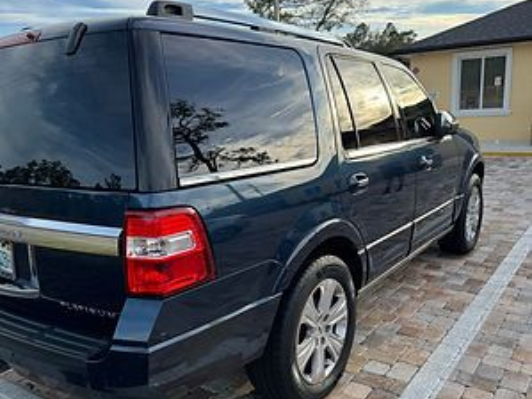 Person wearing black gloves applying ceramic coating to a car's hood.