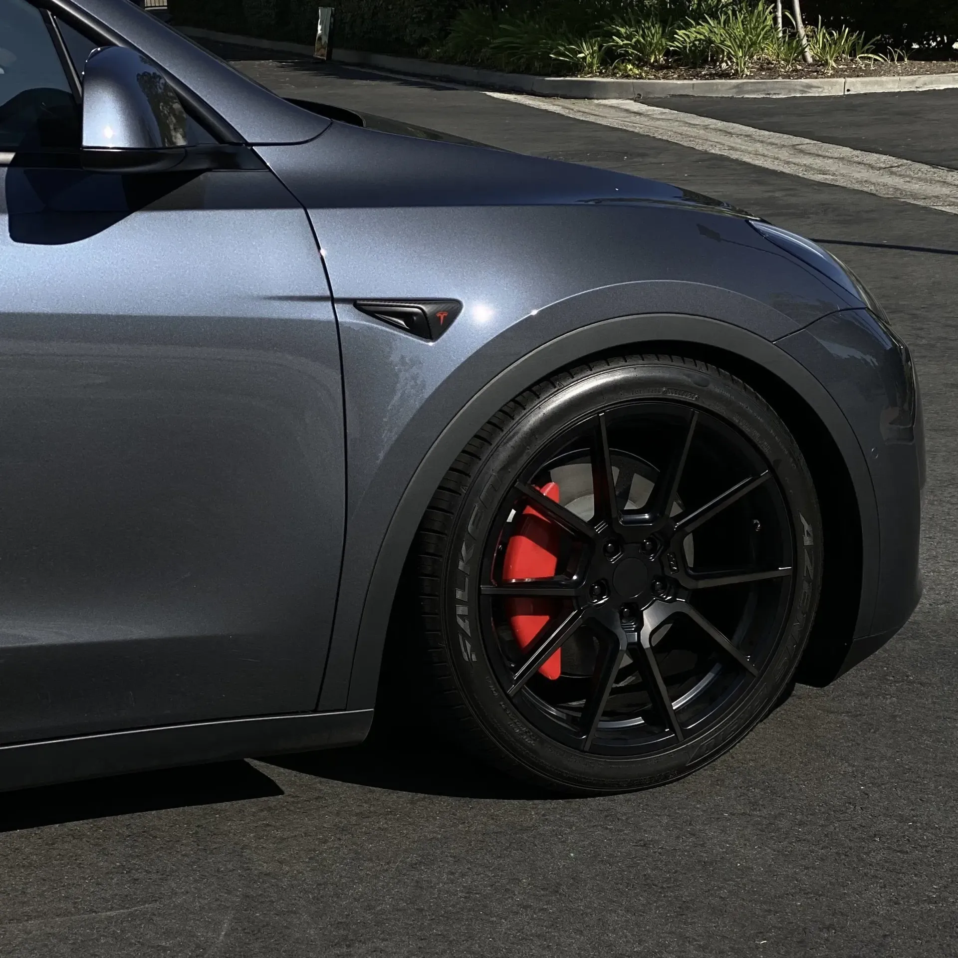 Red sports car in a garage with bright overhead lights.