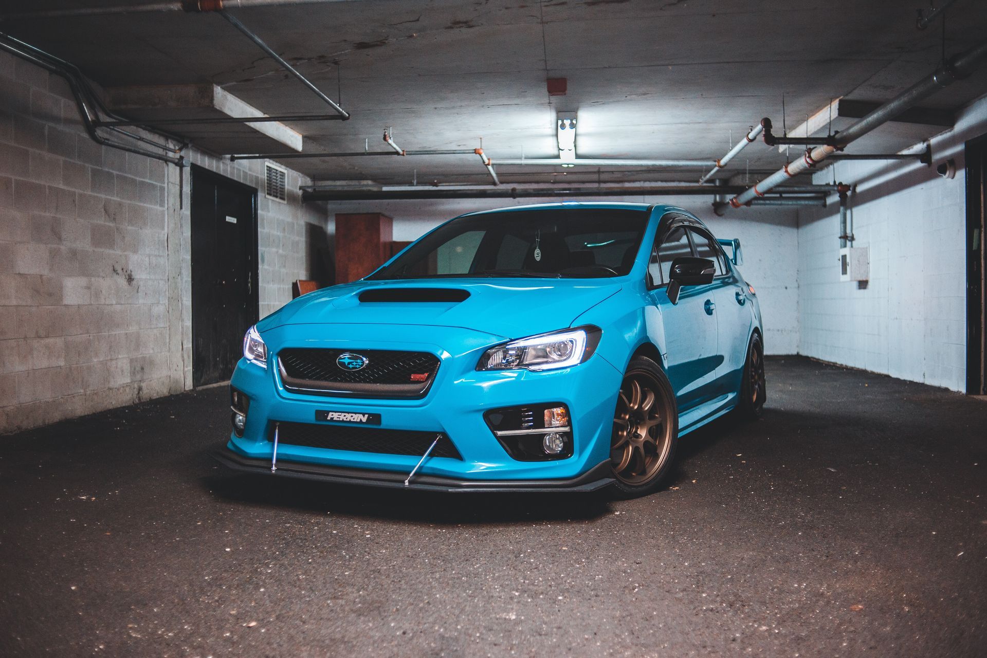 Blue Subaru WRX parked in a dimly lit garage.