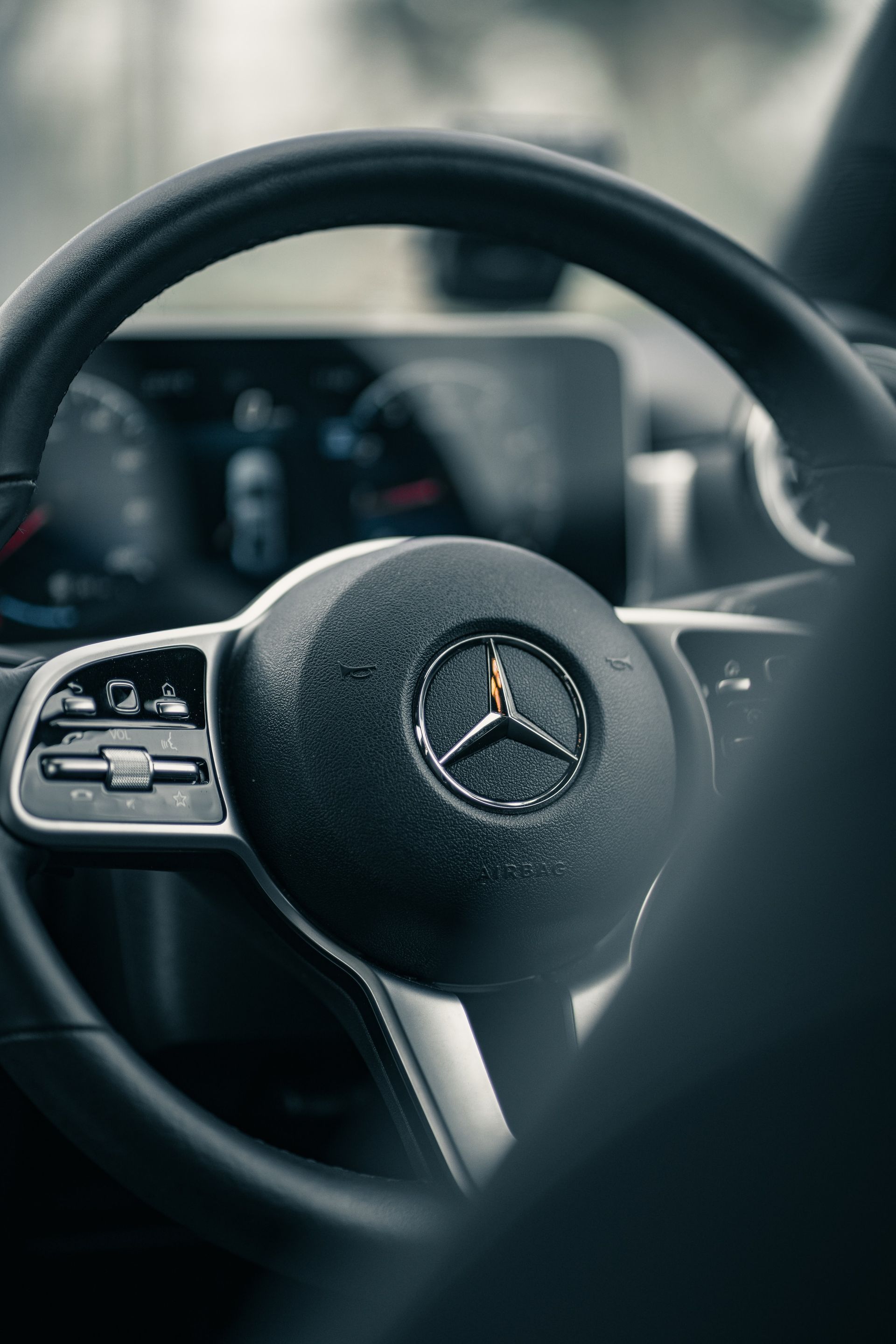 Black Mercedes-Benz steering wheel, silver accents, dashboard visible in background.