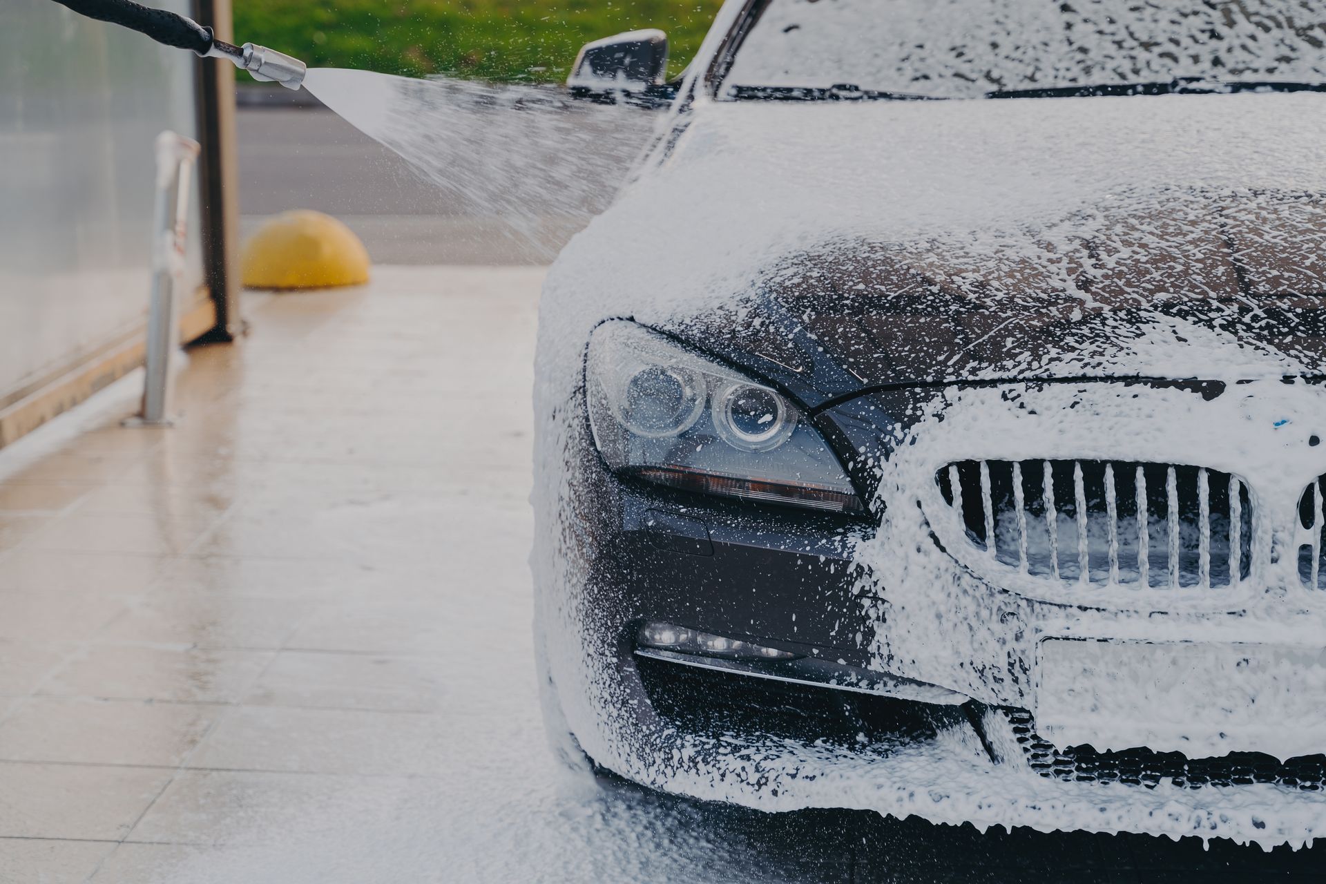 Car being sprayed with foamy soap at a car wash.