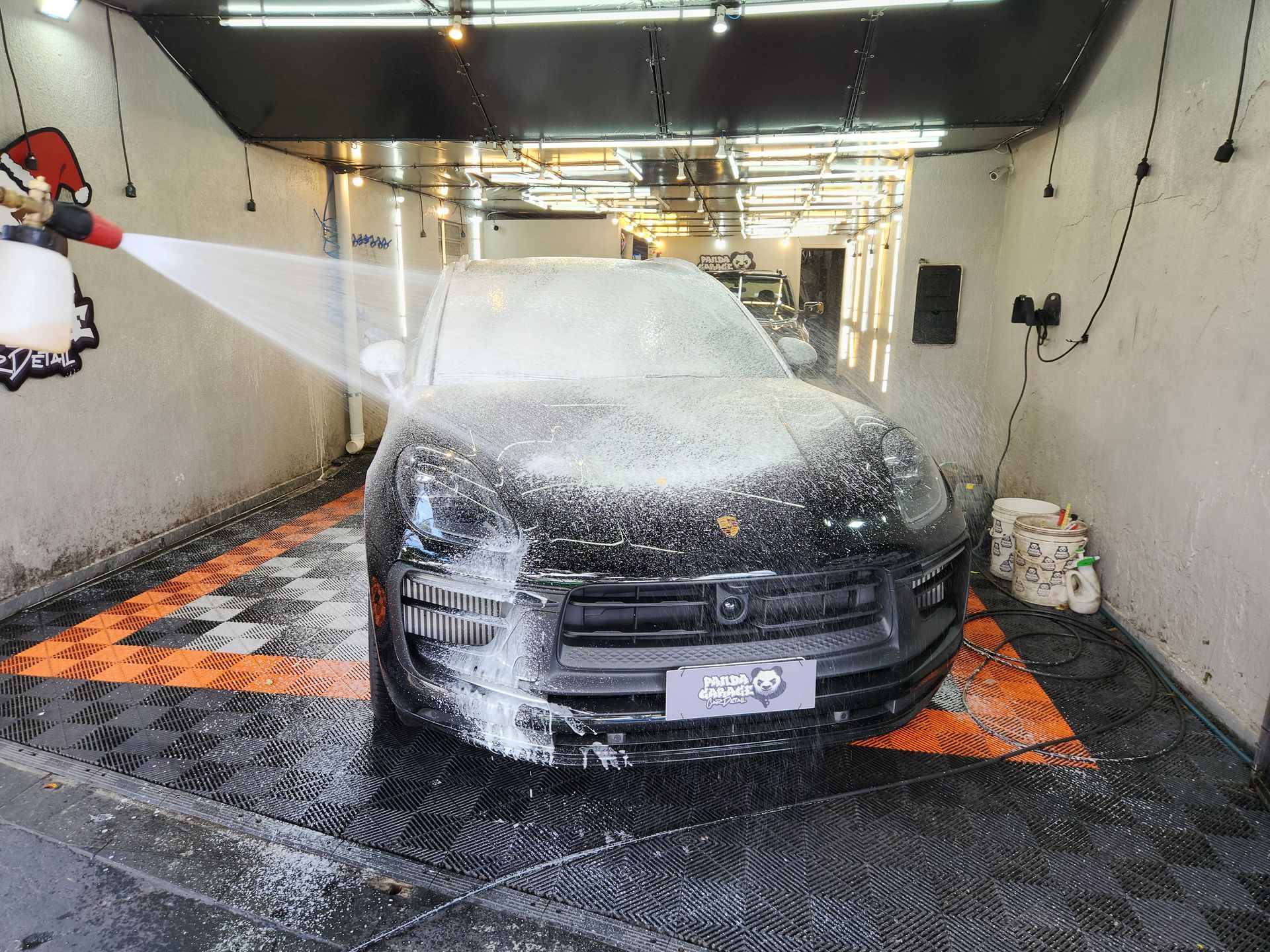 A black car covered in foam being washed at a car wash.