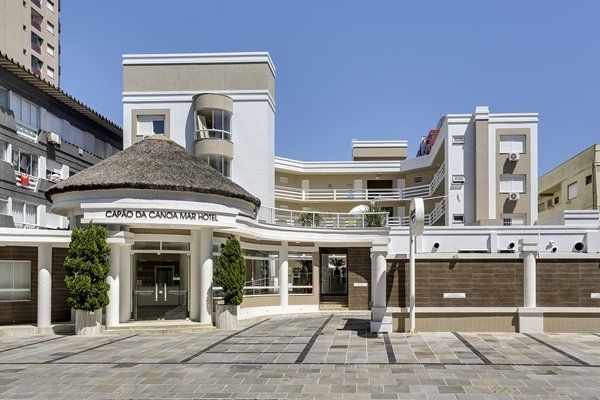 Um grande edifício branco com telhado de palha é cercado por outros edifícios