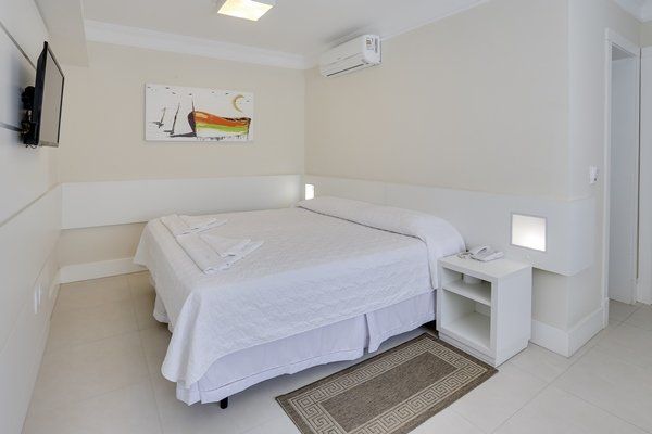 Um quarto de hotel com cama king size e TV de tela plana