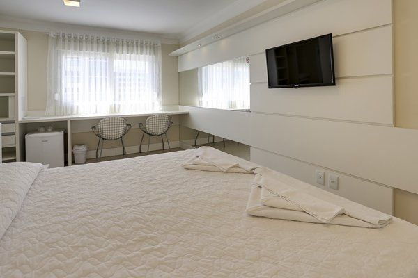 Um quarto de hotel com uma cama grande e uma TV de tela plana na parede.