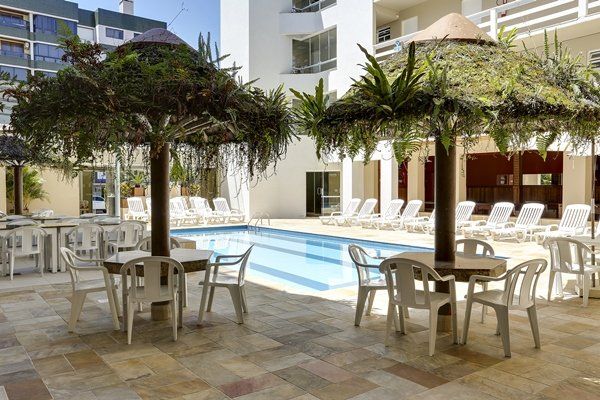 Uma piscina com mesas e cadeiras ao redor