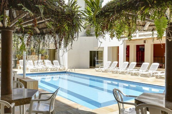 Uma grande piscina com mesas e cadeiras ao redor.