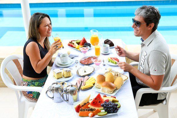 Um homem e uma mulher estão sentados à mesa tomando café da manhã