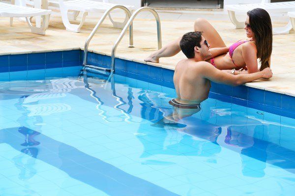 Um homem e uma mulher estão sentados à beira de uma piscina.