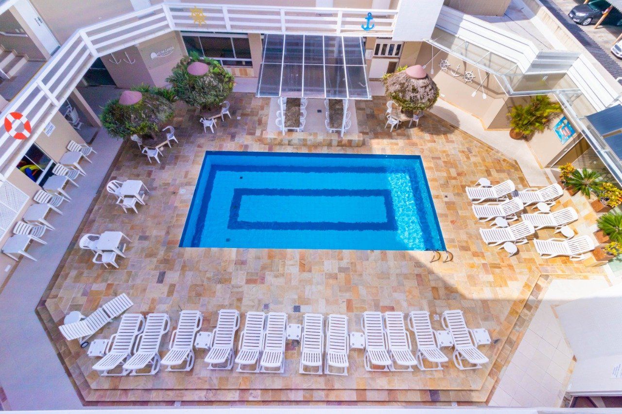 Uma vista aérea de uma grande piscina cercada por cadeiras e mesas.