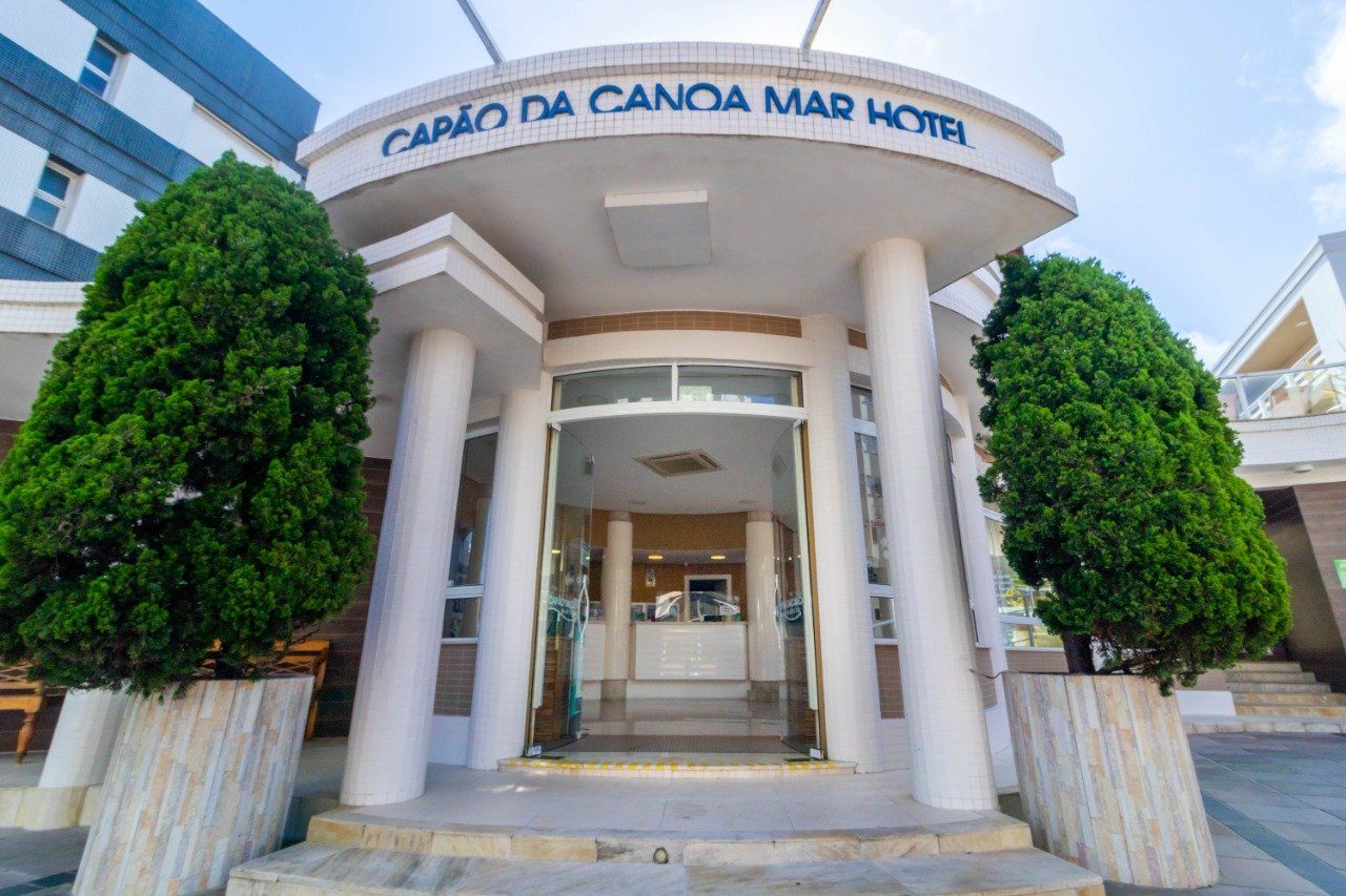 A entrada do hotel canoa mar com árvores na frente