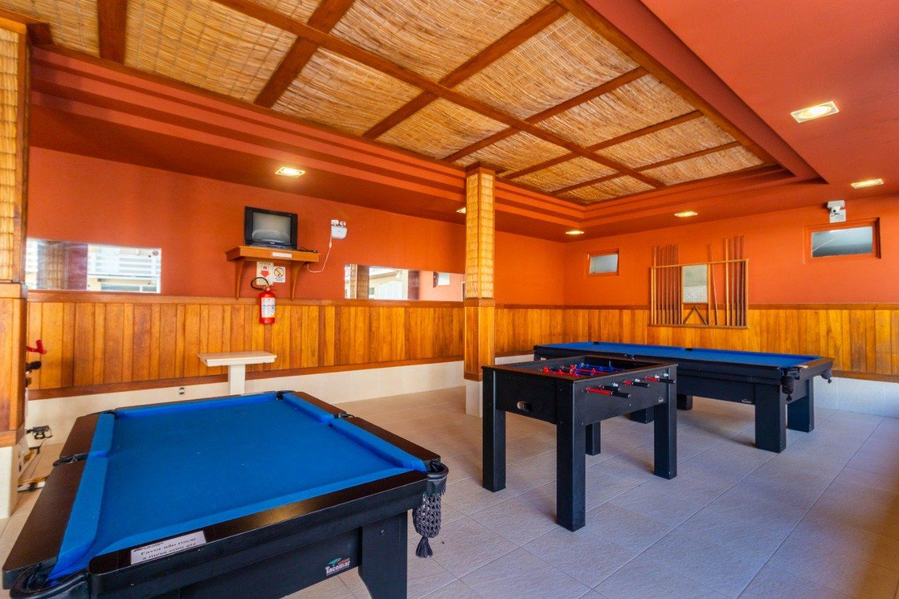 Uma sala de jogos com mesas de sinuca e pebolim