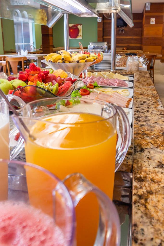 Uma mesa de bufê com uma jarra de suco de laranja e uma jarra de milkshake de morango.