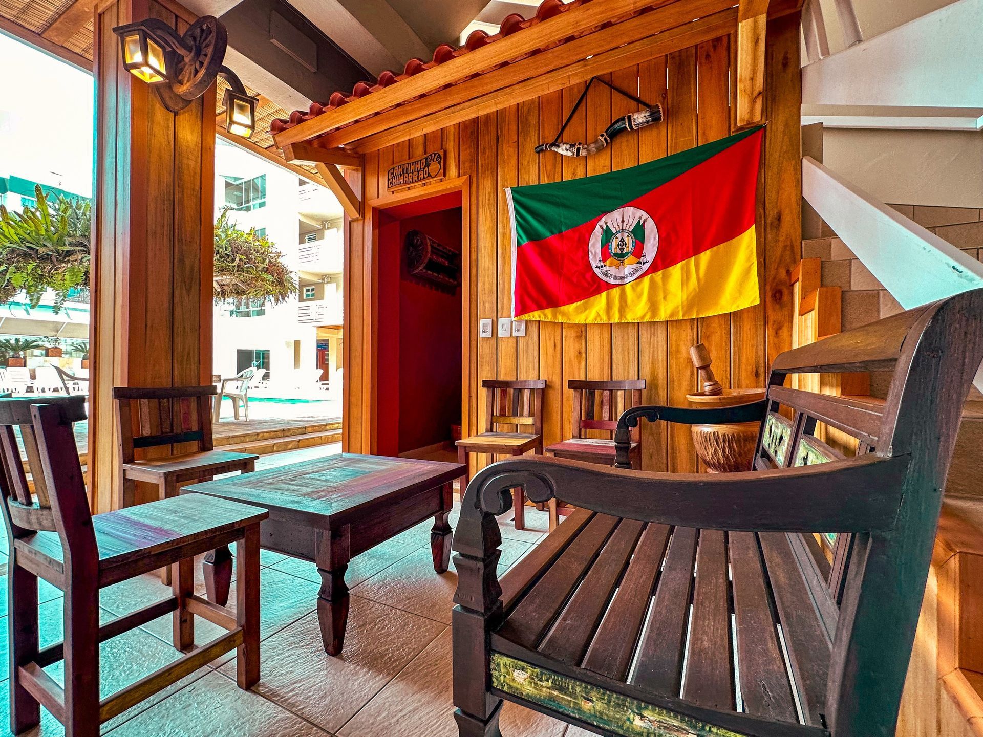 Um banco de madeira está em frente a um prédio de madeira com uma bandeira pendurada na parede.