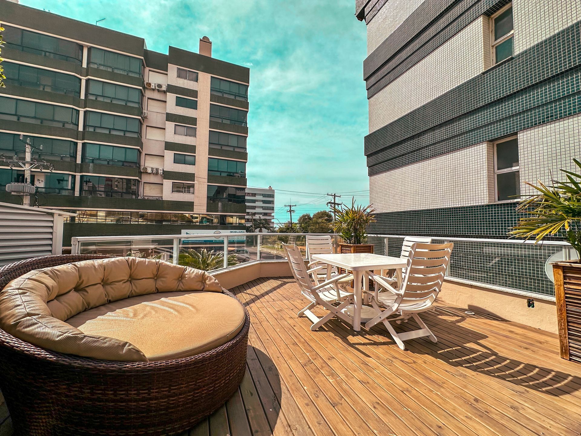 Um deck de madeira com um sofá redondo e uma mesa e cadeiras.