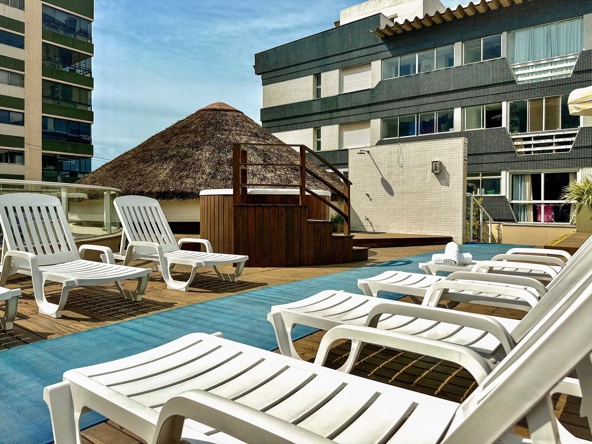 Uma fileira de espreguiçadeiras brancas está alinhada em frente a um prédio.