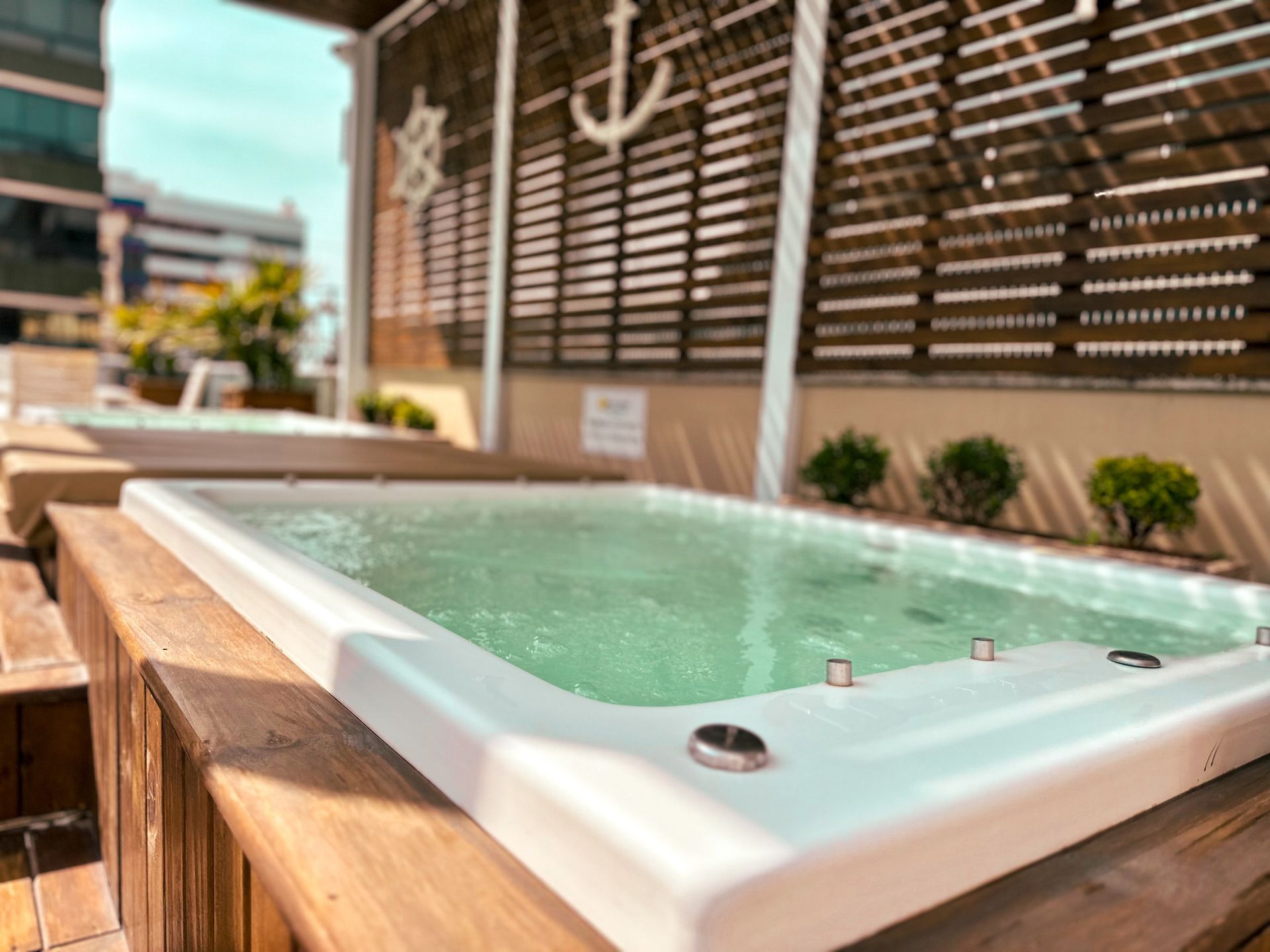 Uma banheira de hidromassagem branca cheia de água verde está no topo de um deck de madeira.