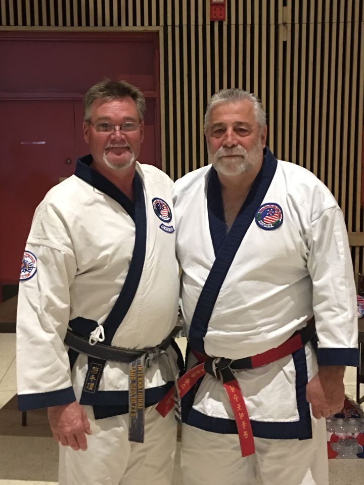 Two men in karate uniforms are posing for a picture