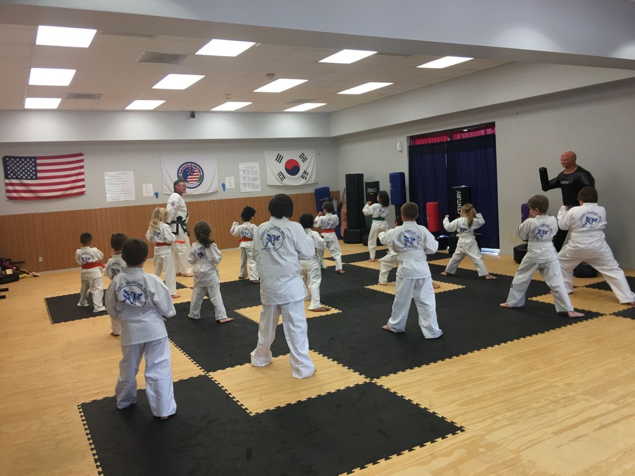 A group of children are practicing martial arts in a gym.