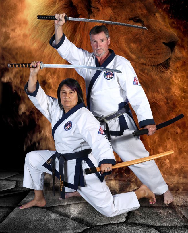 A man and a woman in karate uniforms holding swords.