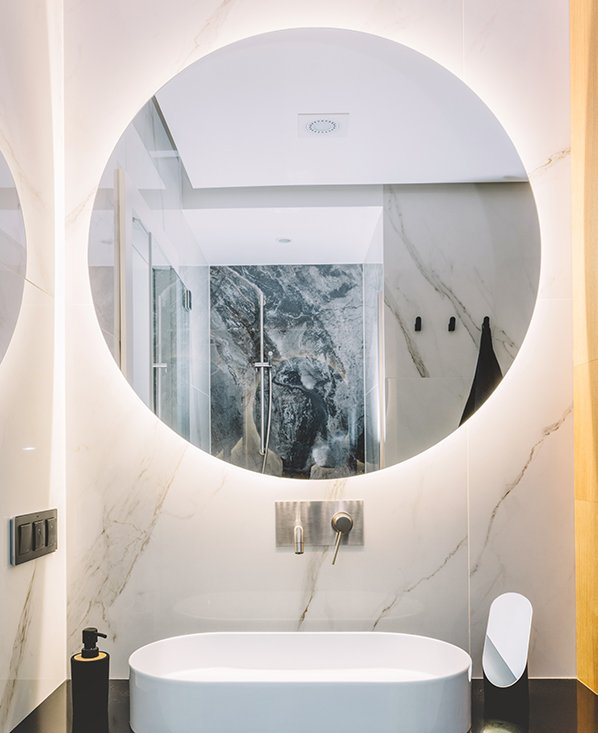 A bathroom with a sink and a round mirror.