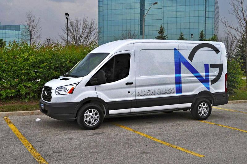 A white van is parked in a parking lot in front of a building.