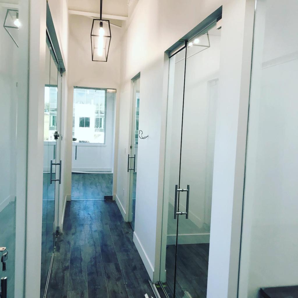 A hallway with glass doors and a light hanging from the ceiling