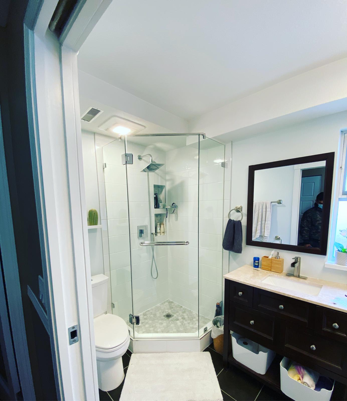 A bathroom with a toilet , sink , shower and mirror.