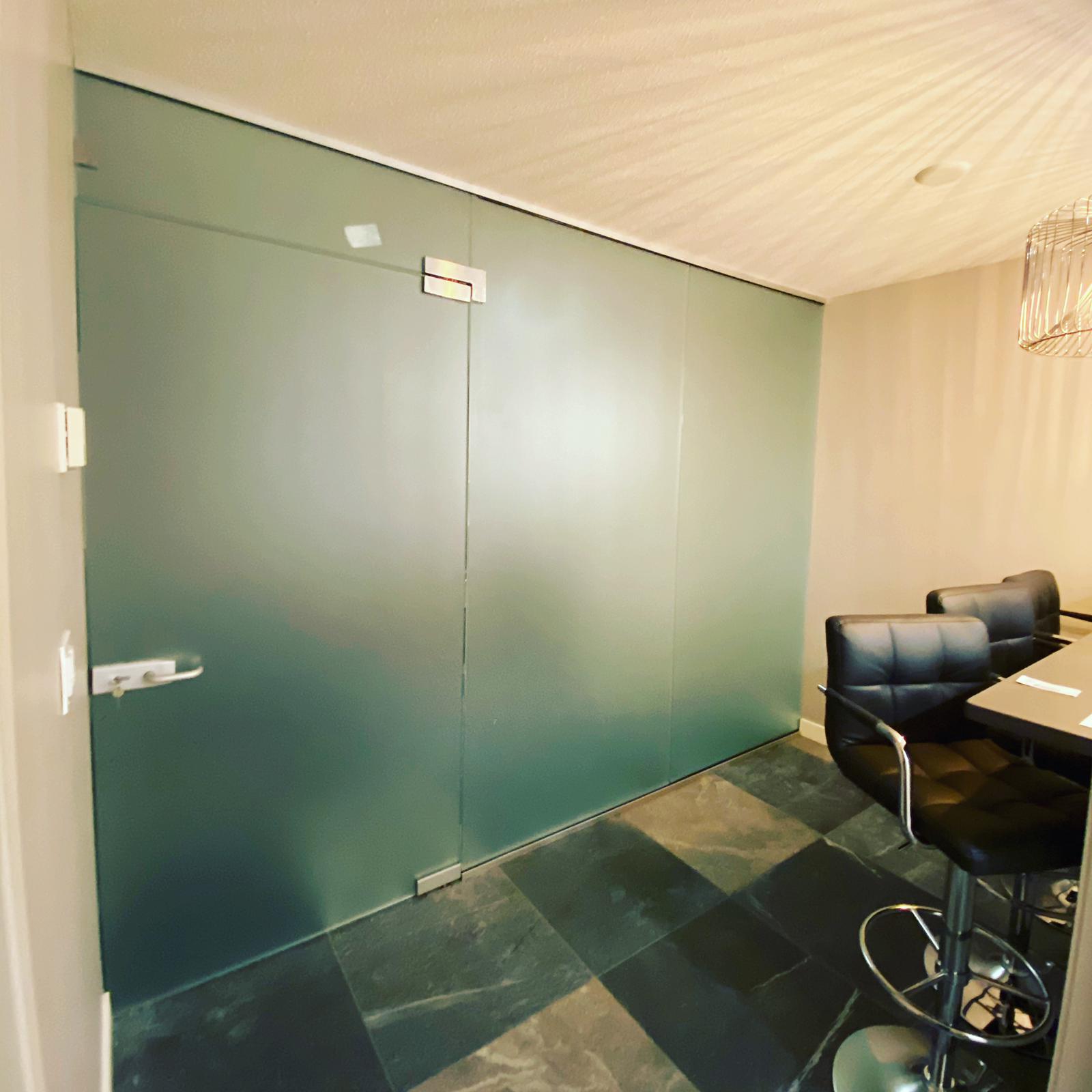 A room with a table and chairs and a glass wall