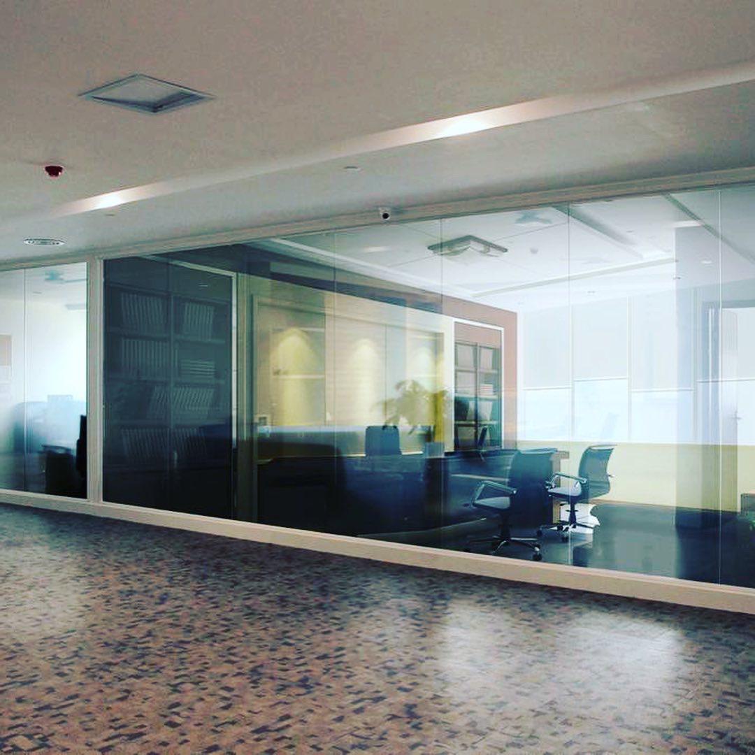 A hallway with a glass wall and chairs in it