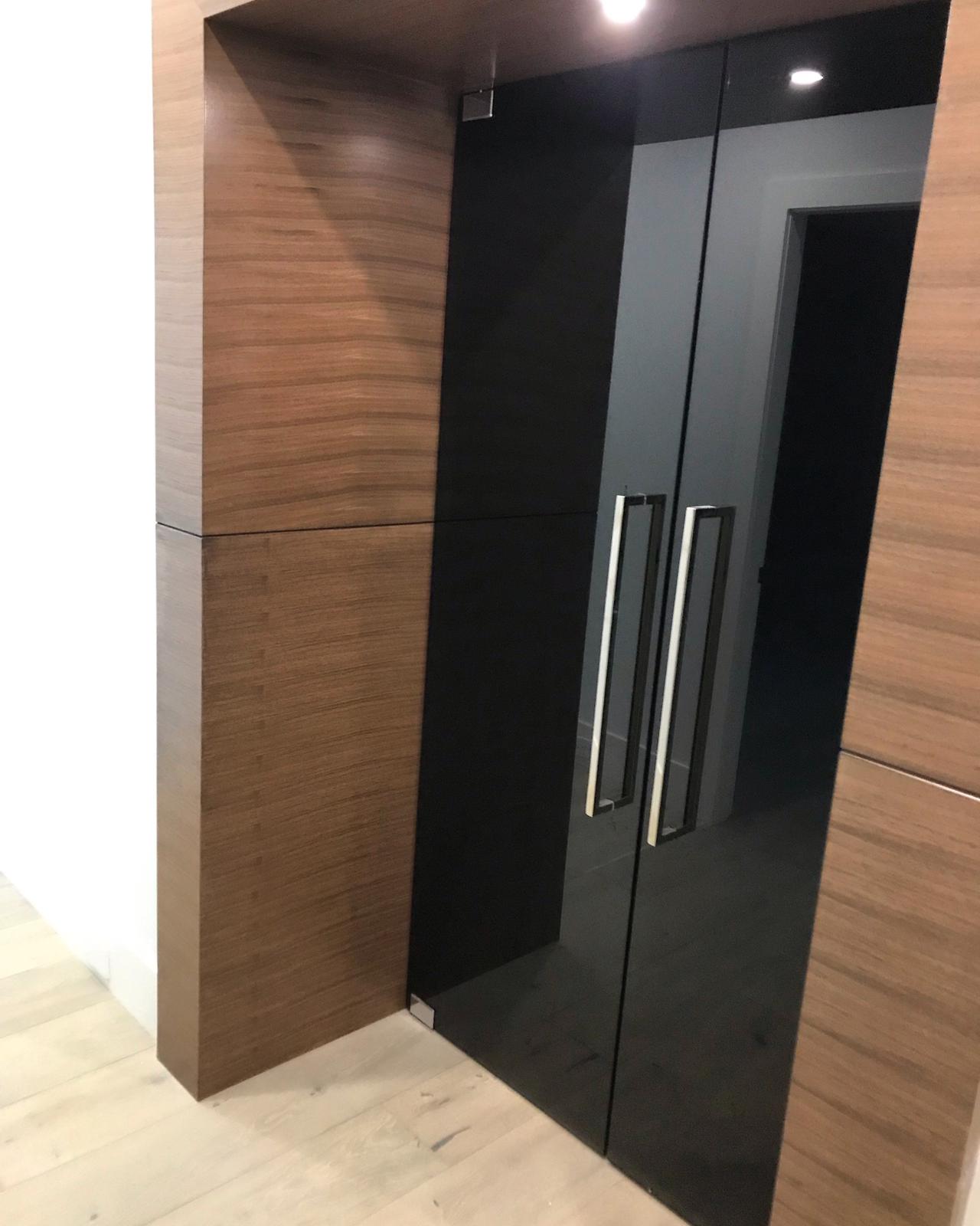 A black glass door with wooden handles in a room.